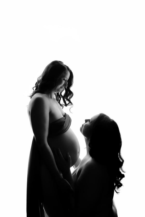 Pregnant couple posing for Nuovo’s Life collection on a white backdrop