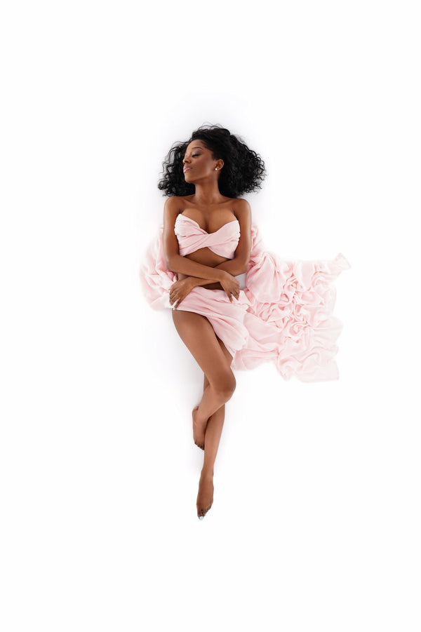 High-key portrait from the Self-Love Collection, individual wrapped in soft pink fabric, exuding elegance and self-embrace on a white backdrop