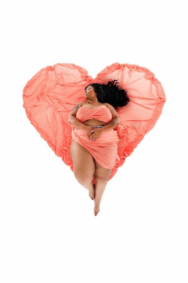 High-key portrait from the Self-Love Collection, individual cradled by a heart-shaped coral fabric, embodying self-love and confidence