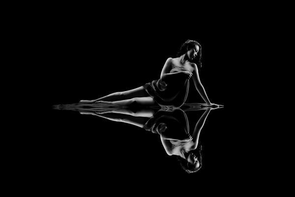 Black and white low-key photograph from the Self-Love Collection, serene reflection of an individual in contemplation with fluid fabric detail