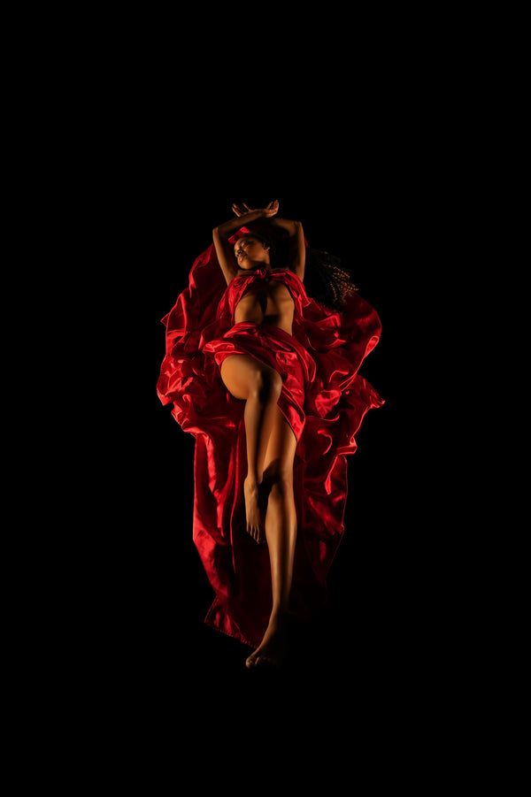 Individual posing for Self-Love collection with dramatic low-key lighting and red satin flowing over and under their body